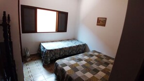 Une petite pièce avec un lit, une table et une fenêtre.