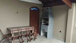 Eine Terrasse mit einem Backofen aus Ziegeln und einem Holztisch.