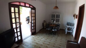 Ein Zimmer mit Fliesenboden, einem Esstisch mit Stühlen, einem weißen Heizkörper und einer Pendelleuchte.