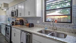 A modern kitchen with white cabinets, a granite countertop, stainless steel appliances, and a window with a view of the outdoors. - SWEET HOME With Private Pool, Patio,& Huge backyard. (Orange Park)