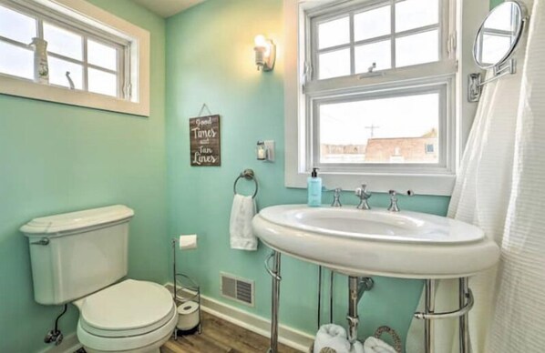 A bathroom with a toilet, sink, and window.