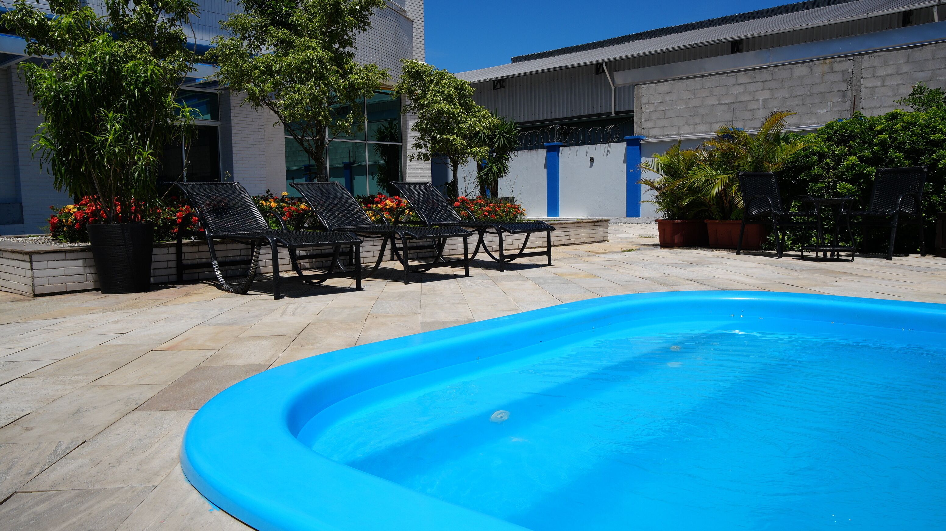 A swimming pool with lounge chairs and potted plants.