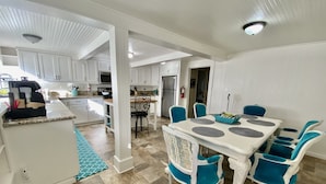 A modern kitchen with white cabinets, a dining area with a white table and teal chairs, and a patterned rug on the floor. - Bethany’s - Charming 4-bedroom Historic Home in Downtown Jackson (Jackson)