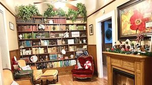 A cozy reading nook with a fireplace, a bookshelf filled with books, and a plush armchair. - Bethany’s - Charming 4-bedroom Historic Home in Downtown Jackson (Jackson)