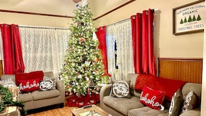 A cozy living room with a decorated Christmas tree, two sofas with red cushions, and a framed sign on the wall. - Bethany’s - Charming 4-bedroom Historic Home in Downtown Jackson (Jackson)