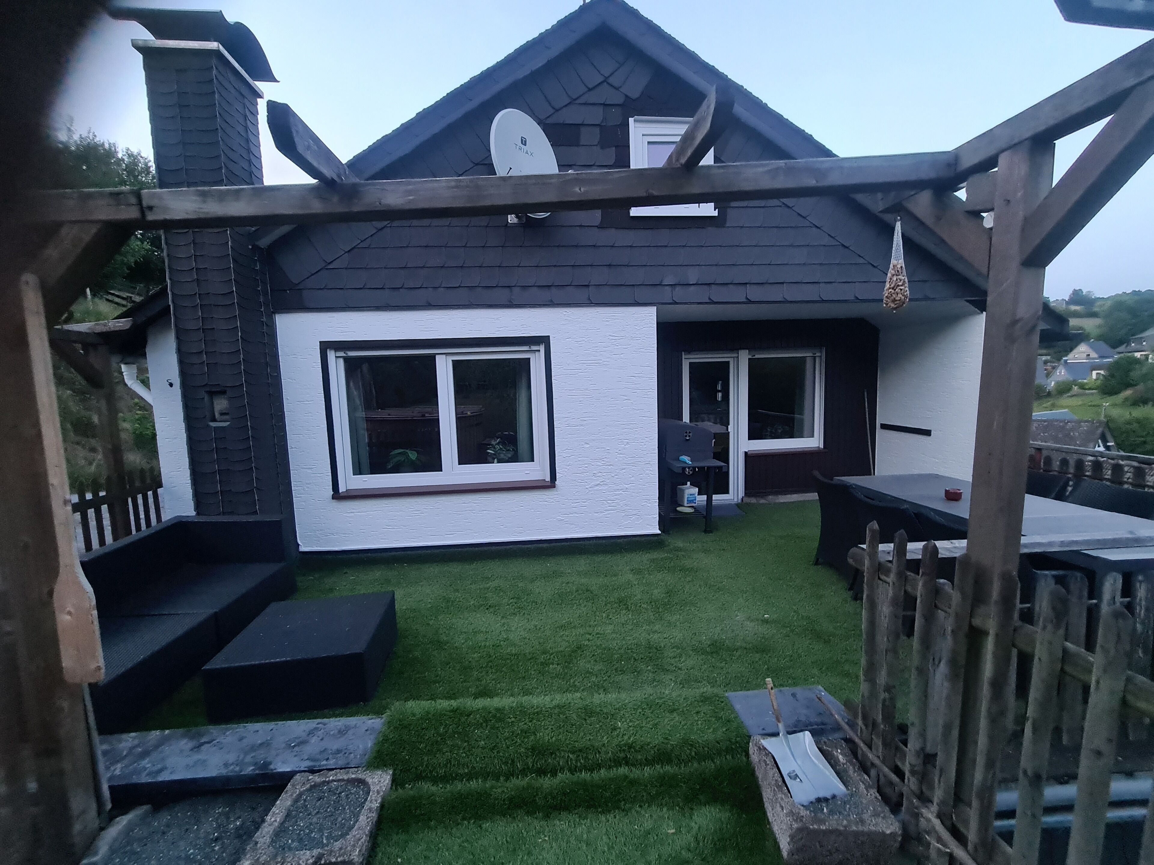 A house with a patio area, a small lawn, and a wooden deck.