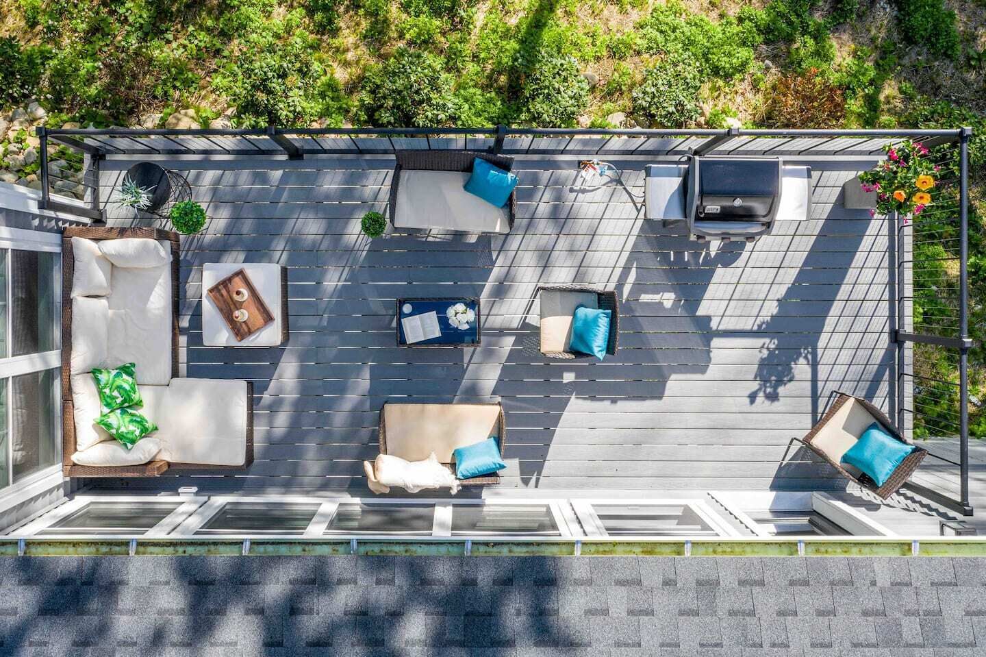 Une terrasse sur le toit dotée de plusieurs espaces de détente, comprenant des canapés et des fauteuils, aménagés sur un toit en pente.