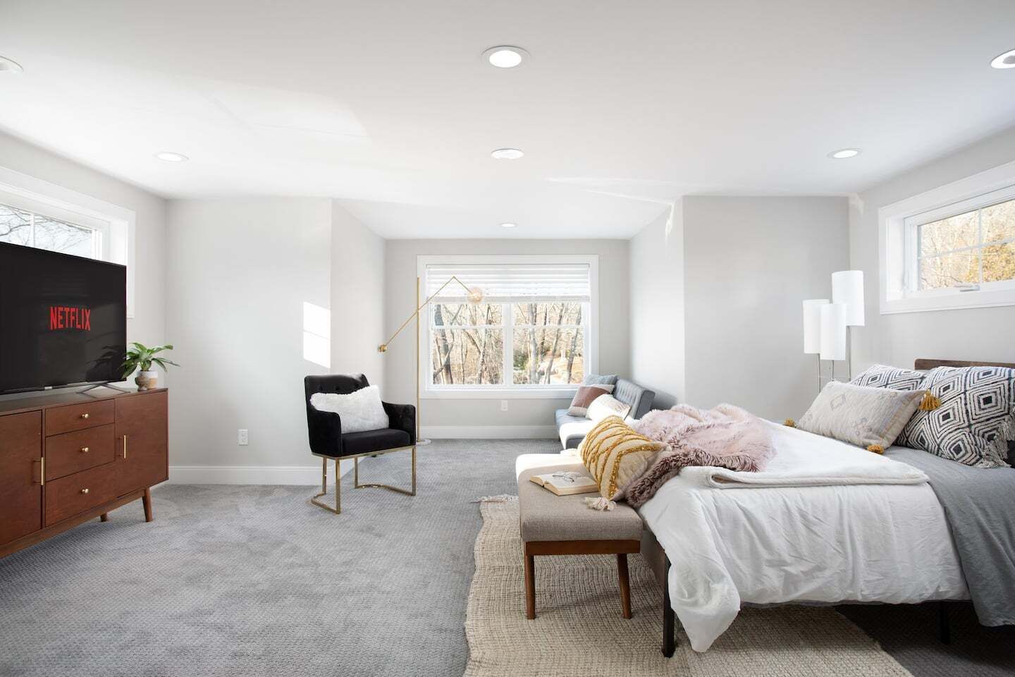 A bedroom with a bed, a chair, a TV, and a window.