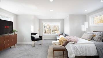 A bedroom with a bed, a chair, a TV, and a window.