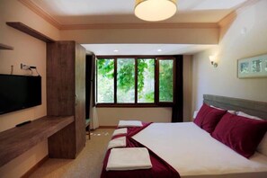 A hotel room with a bed, a TV, a window with a view of greenery, and a wall-mounted light fixture. - Can Termal & Kaplica Apart Hotel (Termal)