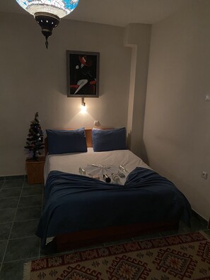 A bedroom with a bed, a small Christmas tree, a painting on the wall, and a patterned rug. - Can Termal & Kaplica Apart Hotel (Termal)