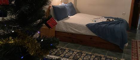 Un dormitorio con una cama, un árbol de Navidad y una alfombra de motivos florales.