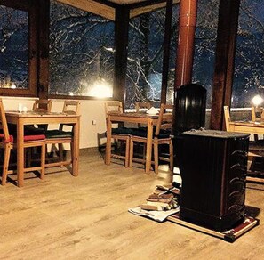 A room with a dining table and chairs, a fireplace, and a view of trees through large windows. - Can Termal & Kaplica Apart Hotel (Termal)