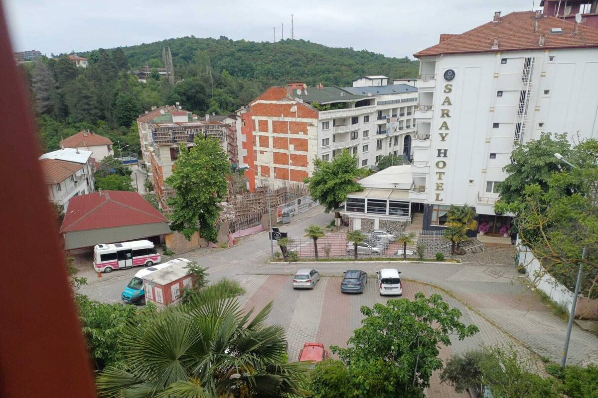 A hotel with multiple floors, a parking area, and surrounding greenery.