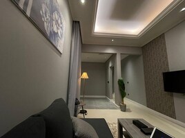 Una sala de estar moderna con un sofá, una mesa de centro, una lámpara y un televisor.