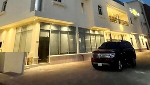 A modern building with a large glass facade, a visible entrance, and a parked car in front. - Voyage Serviced Apartments فوياج للشقق المخدومة (Riyadh)