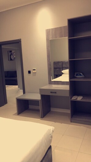 Un dormitorio moderno con cama, mesita de noche, banco empotrado, espejo grande y estantería.