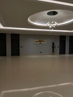 Interior espaçoso e moderno com teto alto, iluminação embutida e um lustre central.