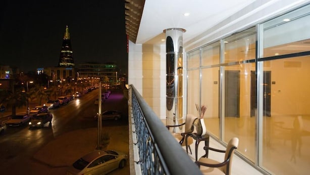 A balcony with a view of a city street at night, featuring a prominent building with a spire. - Voyage Serviced Apartments فوياج للشقق المخدومة (Riyadh)