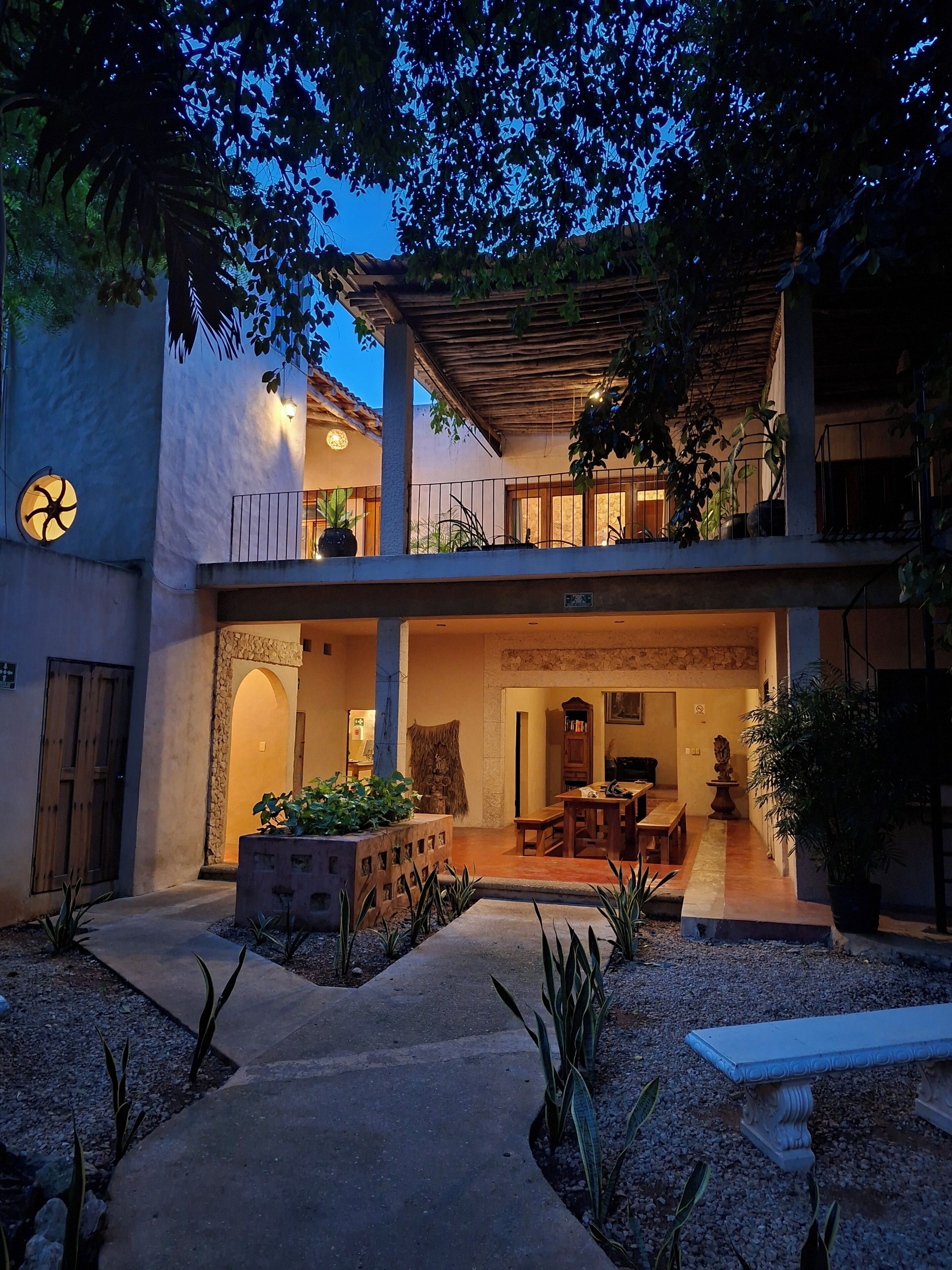 A two-story building with a covered patio, outdoor seating, and a garden area.