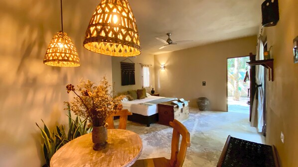 A room with a bed, a dining table with a vase of dried flowers, and hanging wicker lamps. - Hotel Refugio 41 (Valladolid)