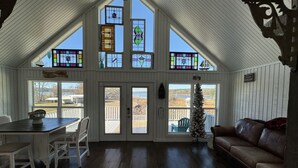 Un interior acogedor con techo alto, pisos de madera, una zona de comedor, una sala de estar con un sofá de cuero y un árbol de Navidad.