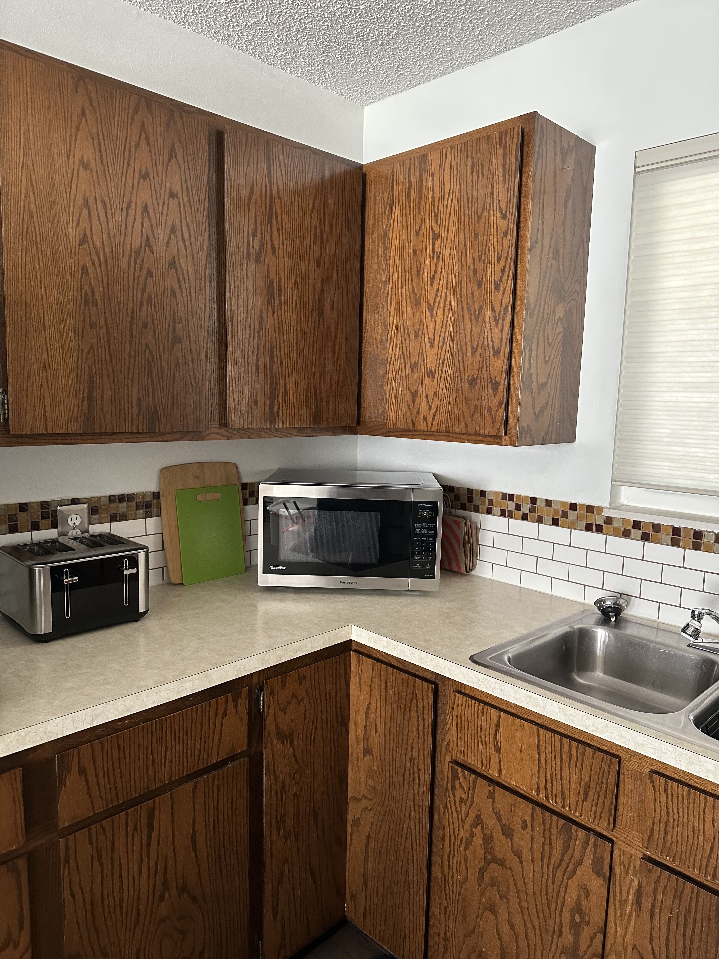 A kitchen with wooden cabinets, a microwave, a toaster, and a sink.