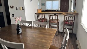 A dining area with a wooden table, white chairs, and a vase of flowers.