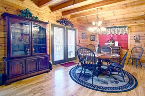 A wooden dining room with a large wooden cabinet, a chandelier, and a red accent wall.