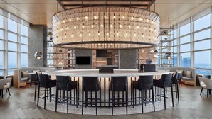 A modern bar area with a circular bar, multiple seating options, and large windows offering city views. - Sheraton Zhaoqing Dinghu (Zhaoqing)