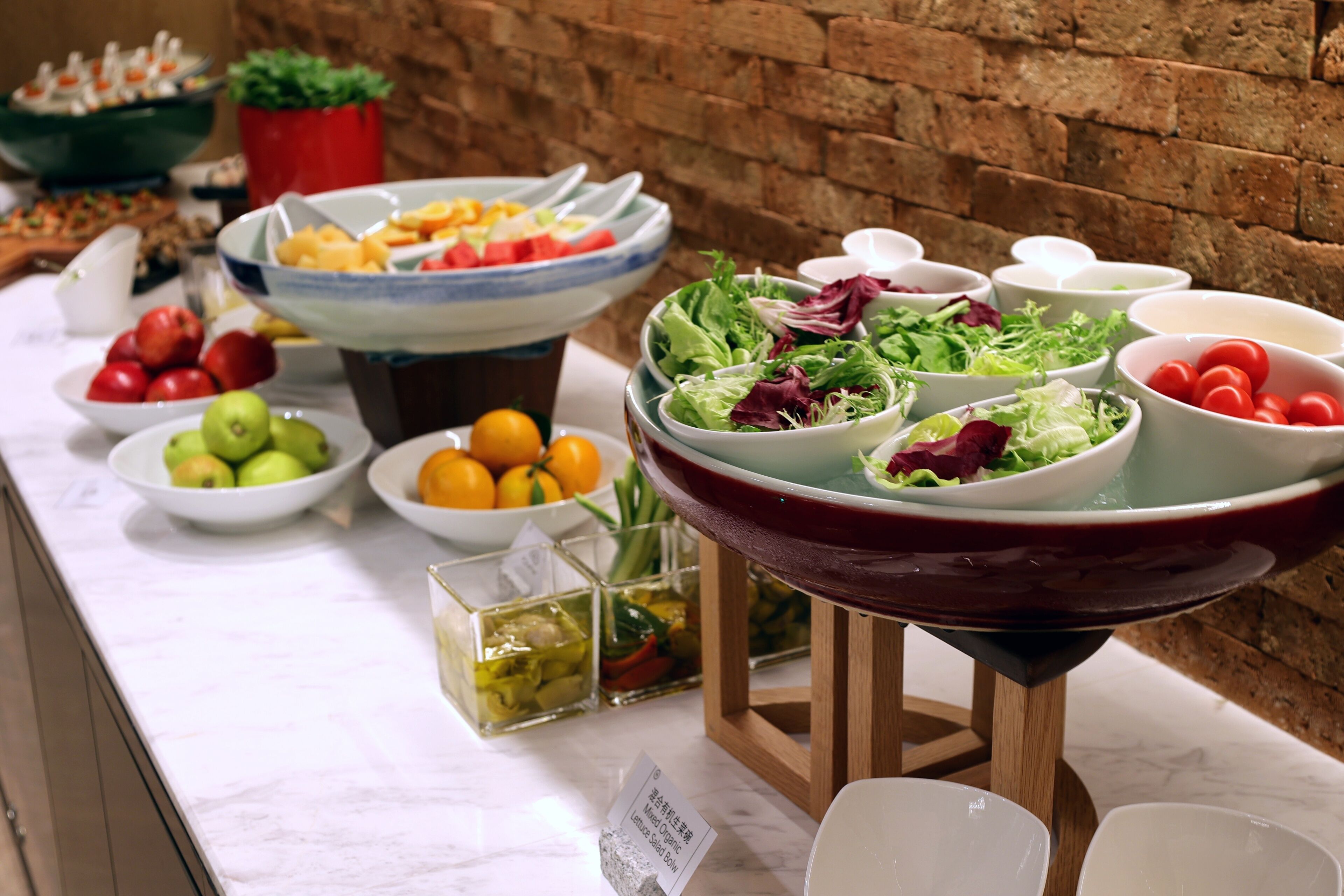A buffet table with various food items including fruits, salads, and vegetables.