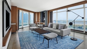 A modern living room with a large flat-screen TV, a sofa, a coffee table, and a floor lamp. - Sheraton Zhaoqing Dinghu (Zhaoqing)