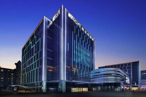 Un hotel moderno con un llamativo letrero de 'Aloft', fachada de vidrio y entrada curva.