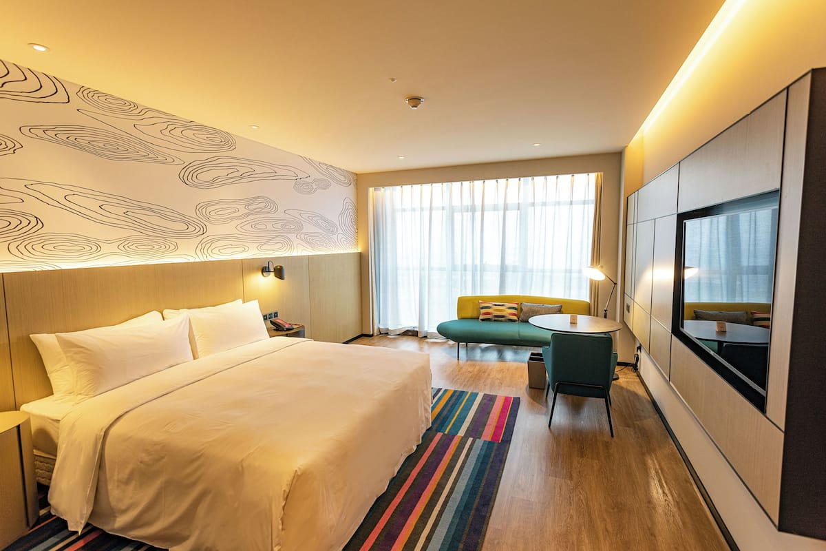 Une chambre d’hôtel avec un grand lit, un canapé, une petite table et un téléviseur.