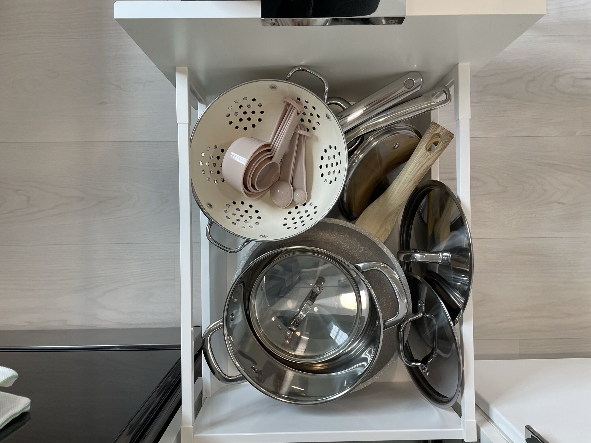 Un tiroir de cuisine contenant des casseroles, des poêles et une passoire.