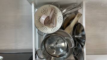 Un tiroir de cuisine contenant des casseroles, des poêles et une passoire.