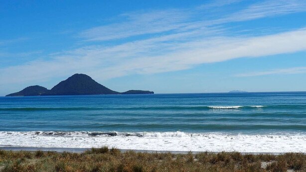 A beach with clear blue water and distant islands. - Paradise on the Sand (Whakatane)