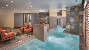 Ein Wellnessbereich mit Whirlpool, Sitzgelegenheiten und einem Wasserfall.