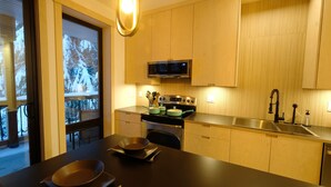 A modern kitchen with wooden cabinets, a stainless steel sink, and a microwave. - Private Suite & Hot Tub @ Red (Rossland)
