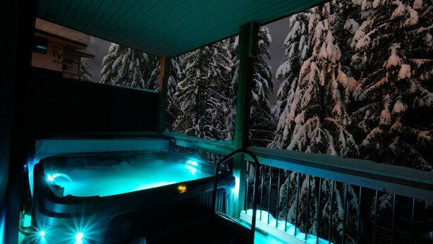 A hot tub on a balcony with snow-covered trees in the background. - Private Suite & Hot Tub @ Red (Rossland)