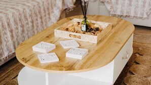 Una mesa de madera con un cajón blanco, una caja de vidrio que contiene una botella y aperitivos, y cuatro cajas blancas decorativas.