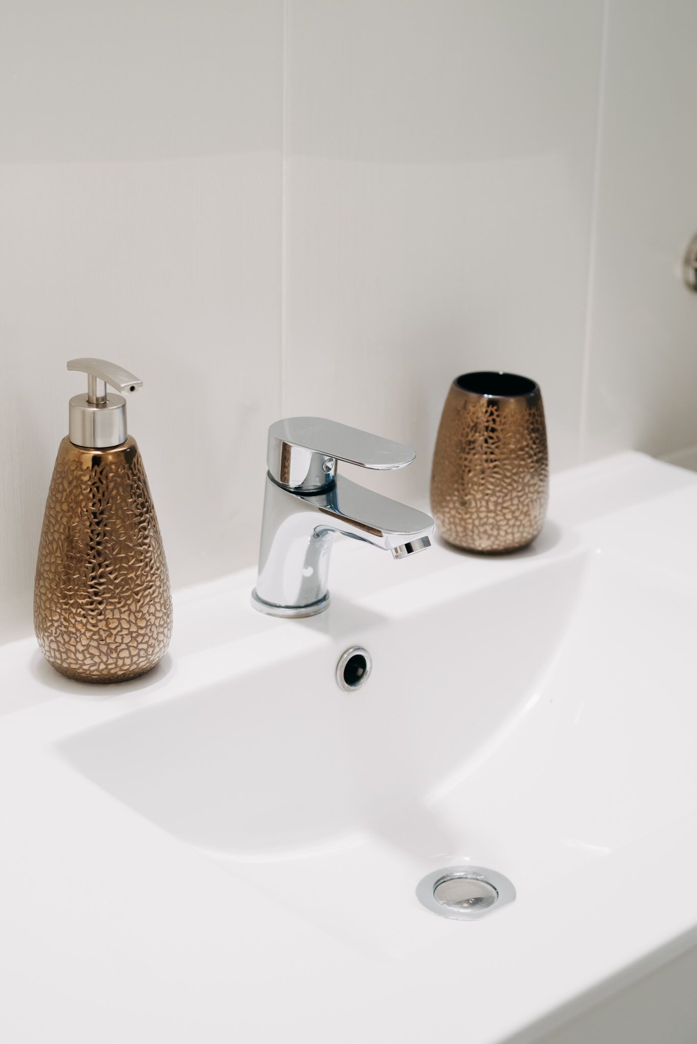 Un lavabo de salle de bain avec un robinet chromé et un distributeur de savon à surface texturée.