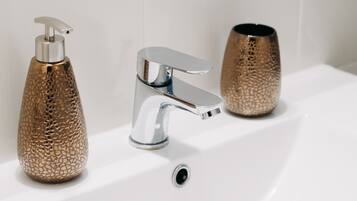 Un lavabo de salle de bain avec un robinet chromé et un distributeur de savon à surface texturée.