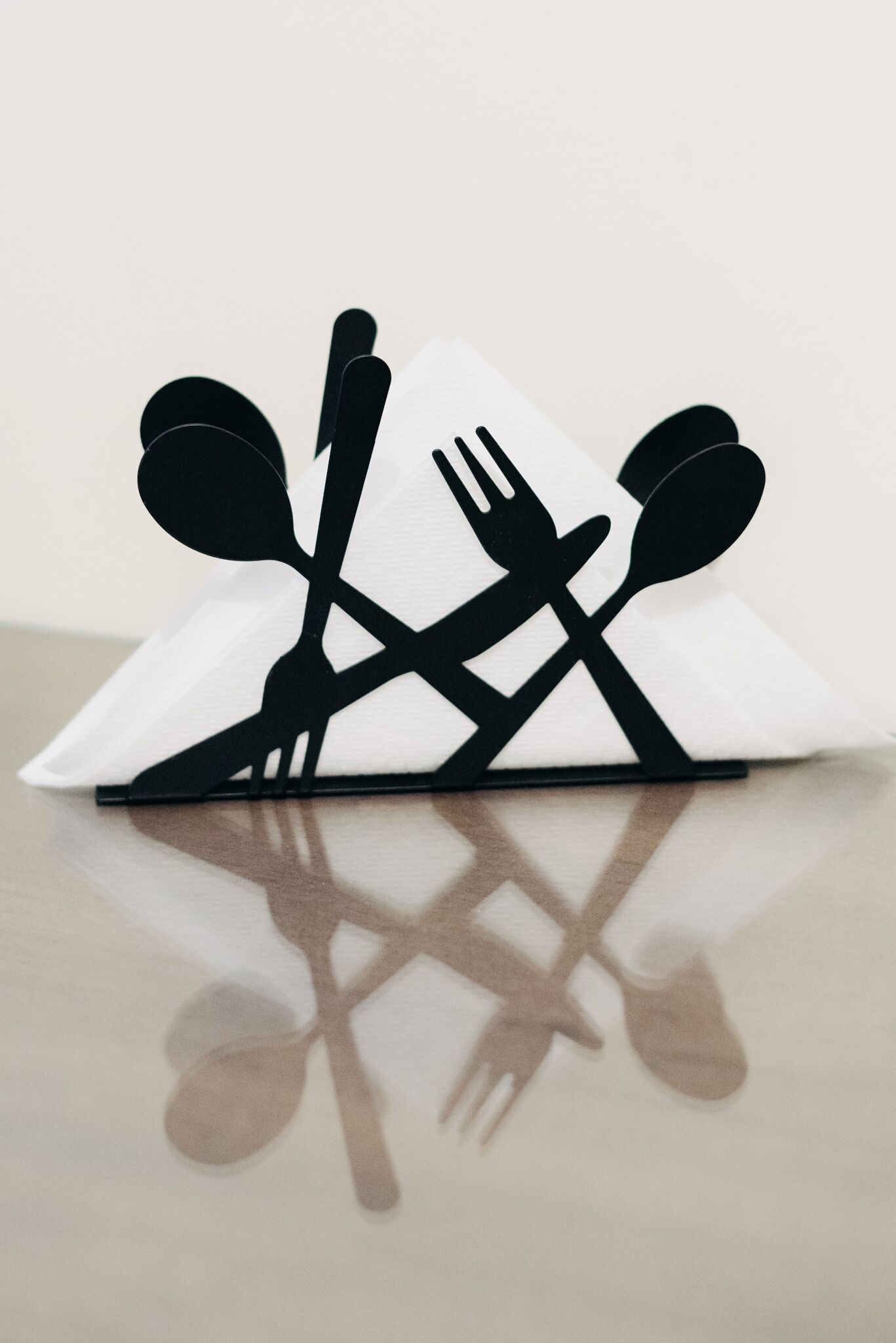 A black and white paper cut-out of a dining set on a white napkin.