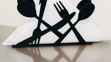 A black and white paper cut-out of a dining set on a white napkin.