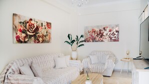 Una sala de estar moderna con sofá, sillón, mesa de centro y obras de arte en las paredes.