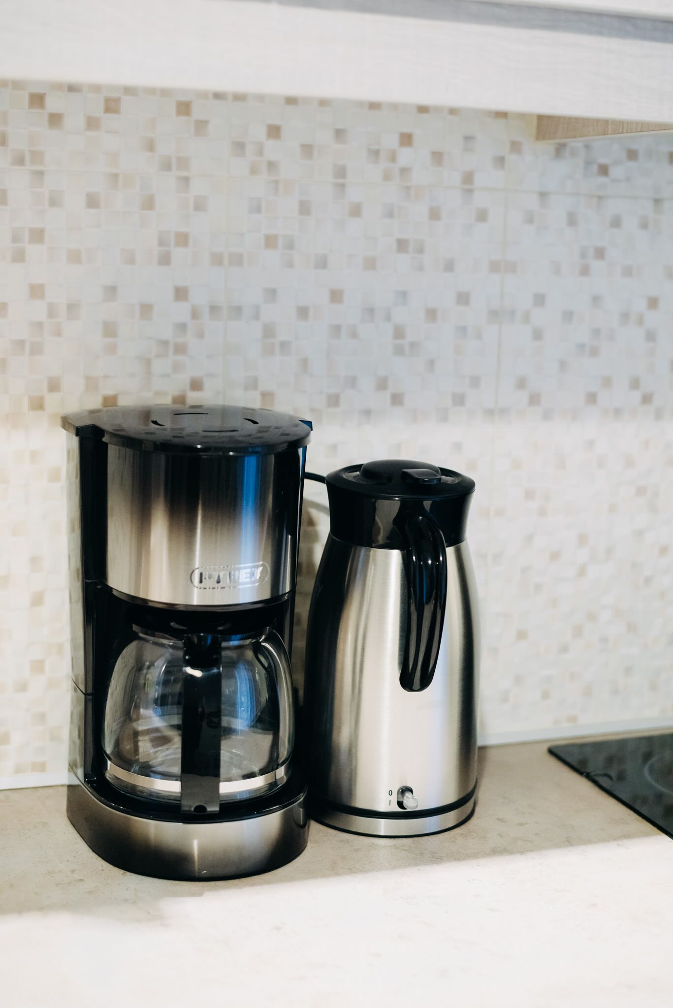 A coffee maker and a thermos on a kitchen counter.