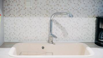 Een keukenkraan met een moderne kraan en een betegelde spatwand.