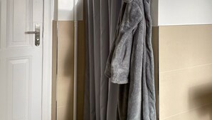 Een badkamer met een witte deur, grijze douchegordijnen en een grijze badjas aan een haak.