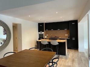 Una cocina moderna con gabinetes negros, una isla de madera y dos taburetes de bar.